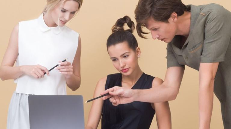 3 Personas mirando hacia una laptop.
