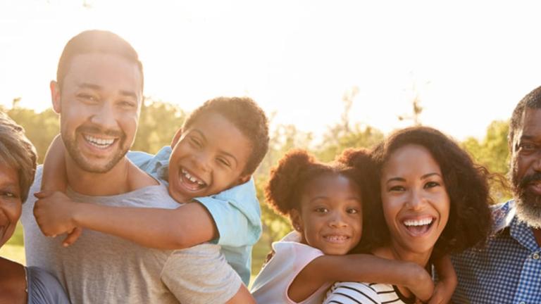 Familia conformada por niños, padres y abuelos riéndose.